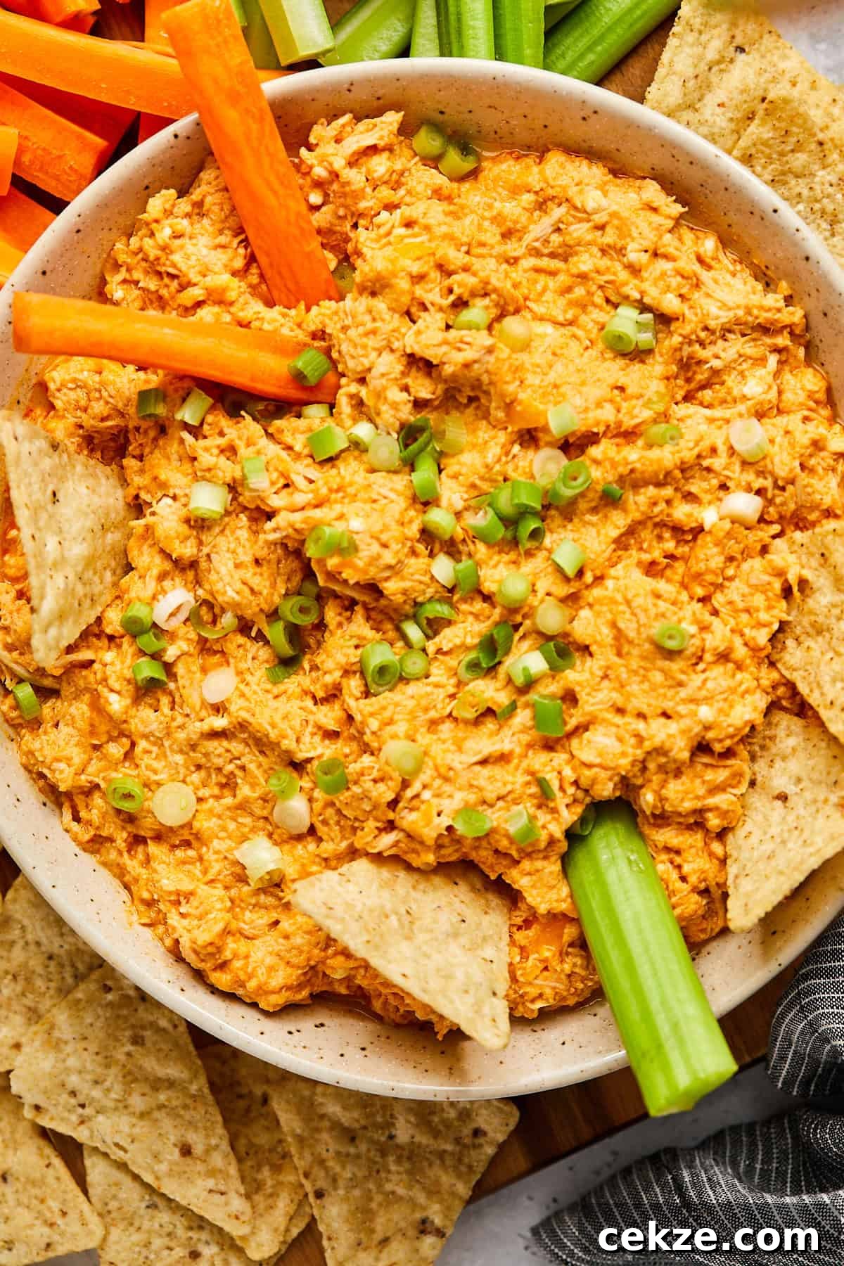 carrot sticks and celery sticks dipping into a bowl of slow cooker buffalo chicken dip 