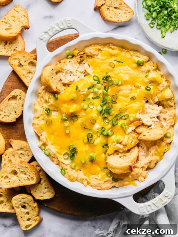protein Maryland crab dip topped with green onions in a white Staub baking dish surrounded by gluten free baguette slices