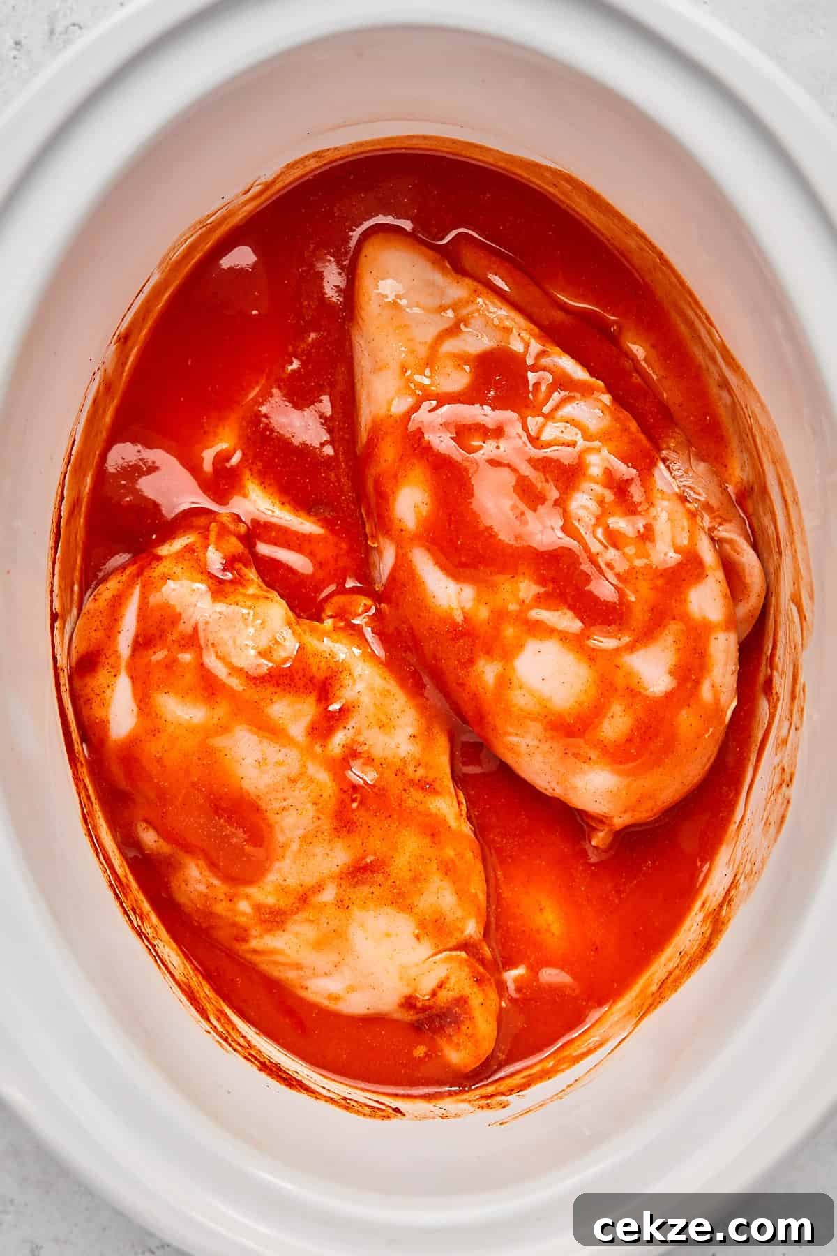 raw chicken tossed in sauce in a crock pot