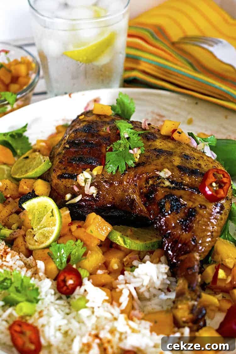 Jerked chicken quarter on plate of fruit and rice