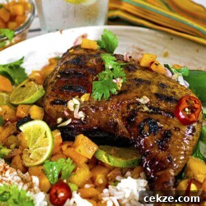 Jerked chicken quarter on plate of fruit and rice