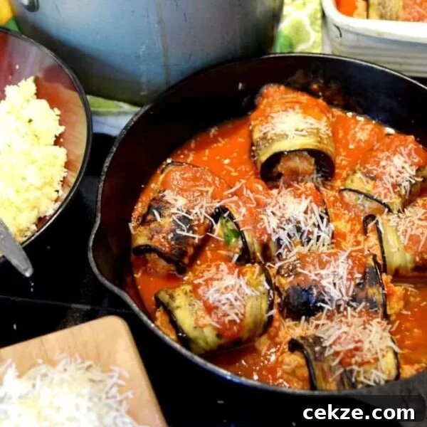 A skillet with rolled eggplant and tomato sauce