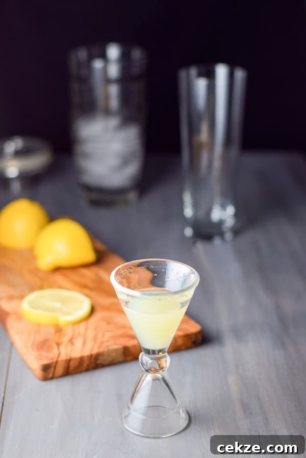 lemon measured out with a wooden board with cut lemons. There is a cocktail shaker and glass in the background