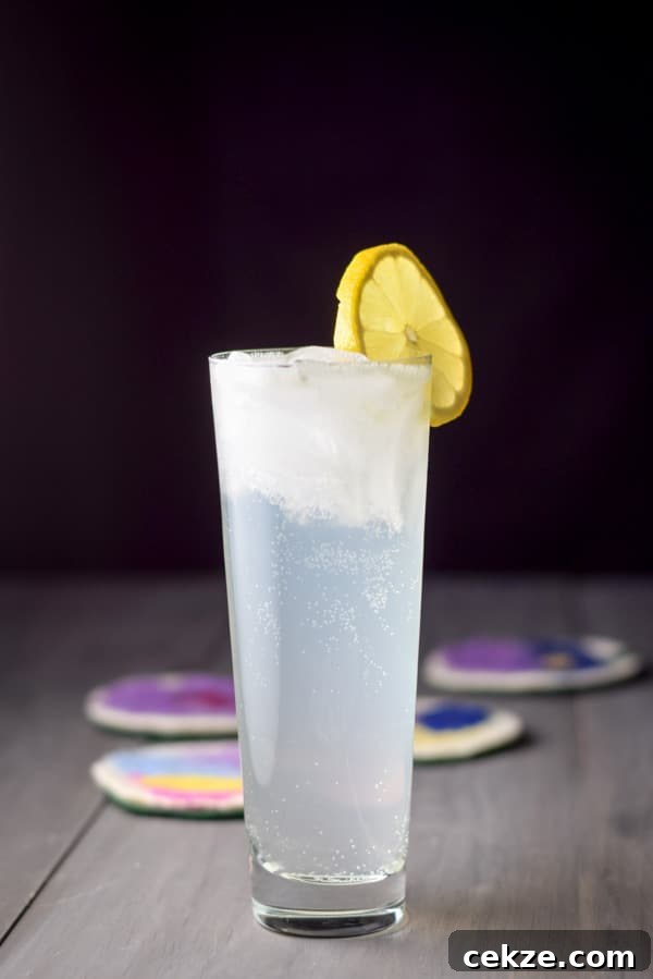 Vertical view of the cloudy cocktail in a flared glass with lemon as the garnish