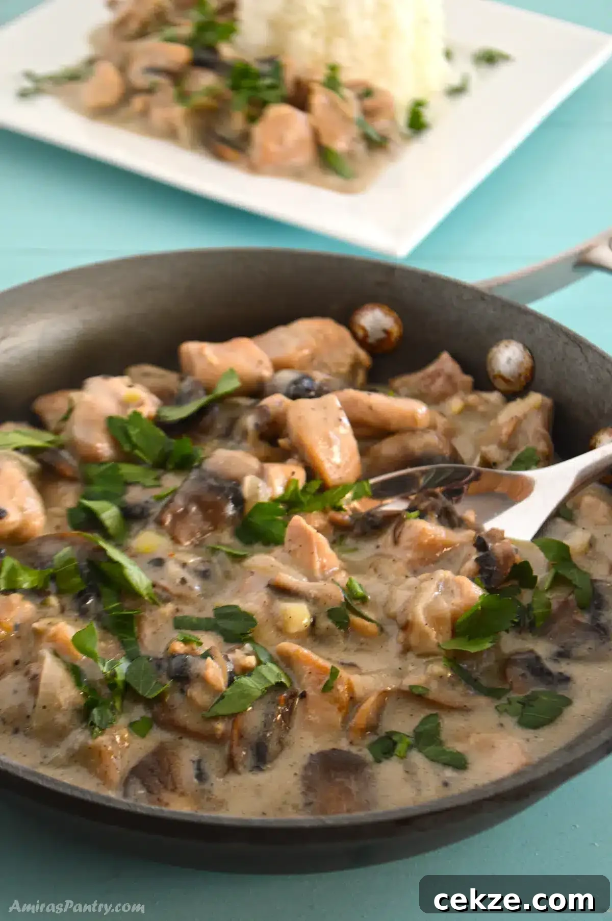 Creamy Garlic Mushroom Chicken Skillet Recipe 2 A skillet with chicken and mushrooms and a spoon.