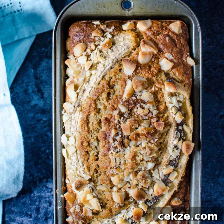 A loaf of coconut macadamia banana bread in a loaf pan.
