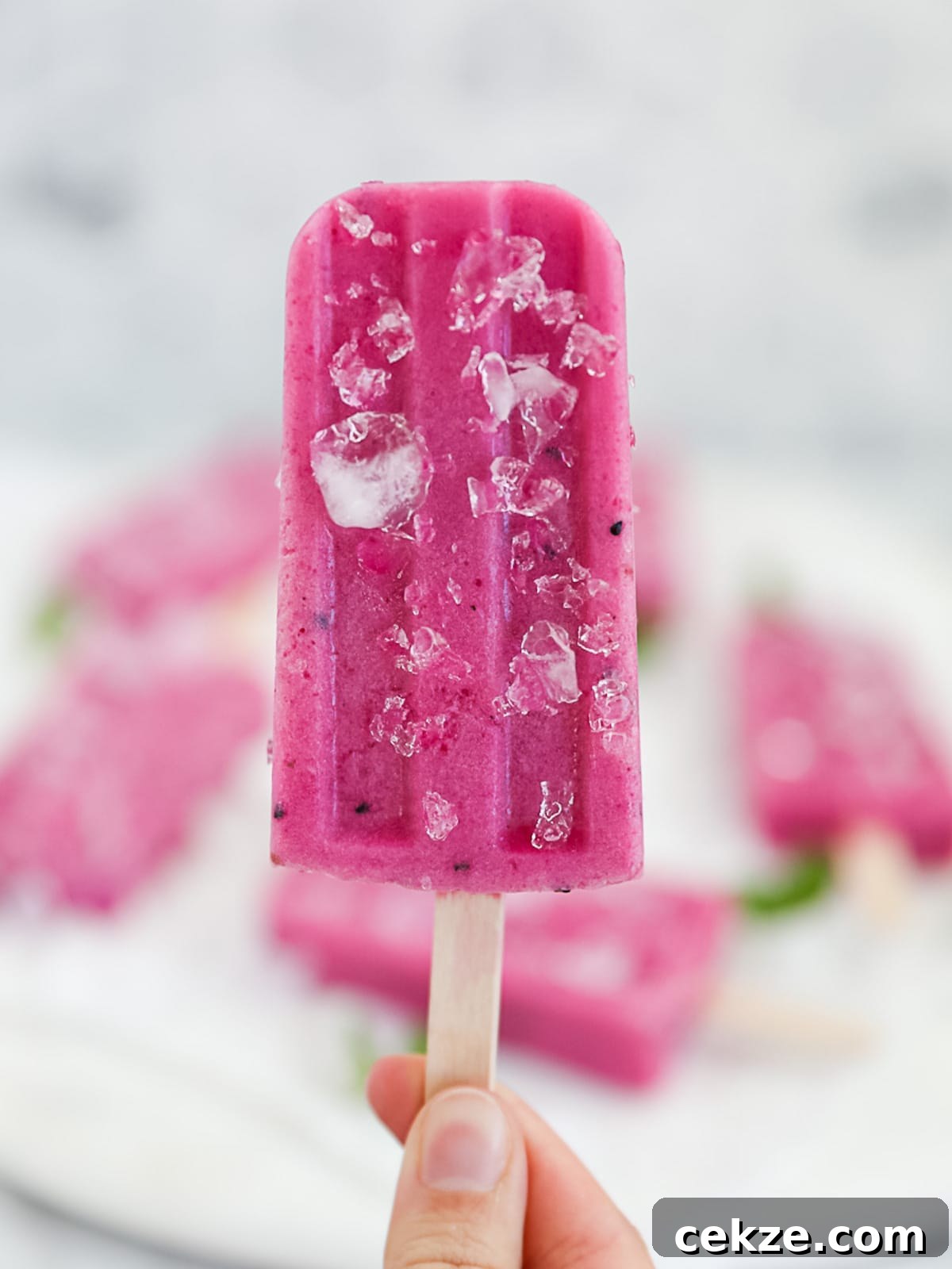 Refreshing Dragon Fruit Popsicle Recipe for Summer Treats 9 A hand holding up a hot pink popsicle