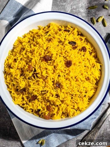 Easy yellow rice with raisons in a whilte bowl.