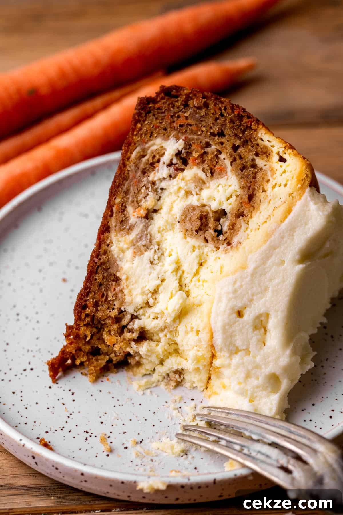Carrot Cake Cheesecake Recipe: Moist Layered Dessert with Cream Cheese Frosting 13 Slice of carrot cake cheesecake on a plate.