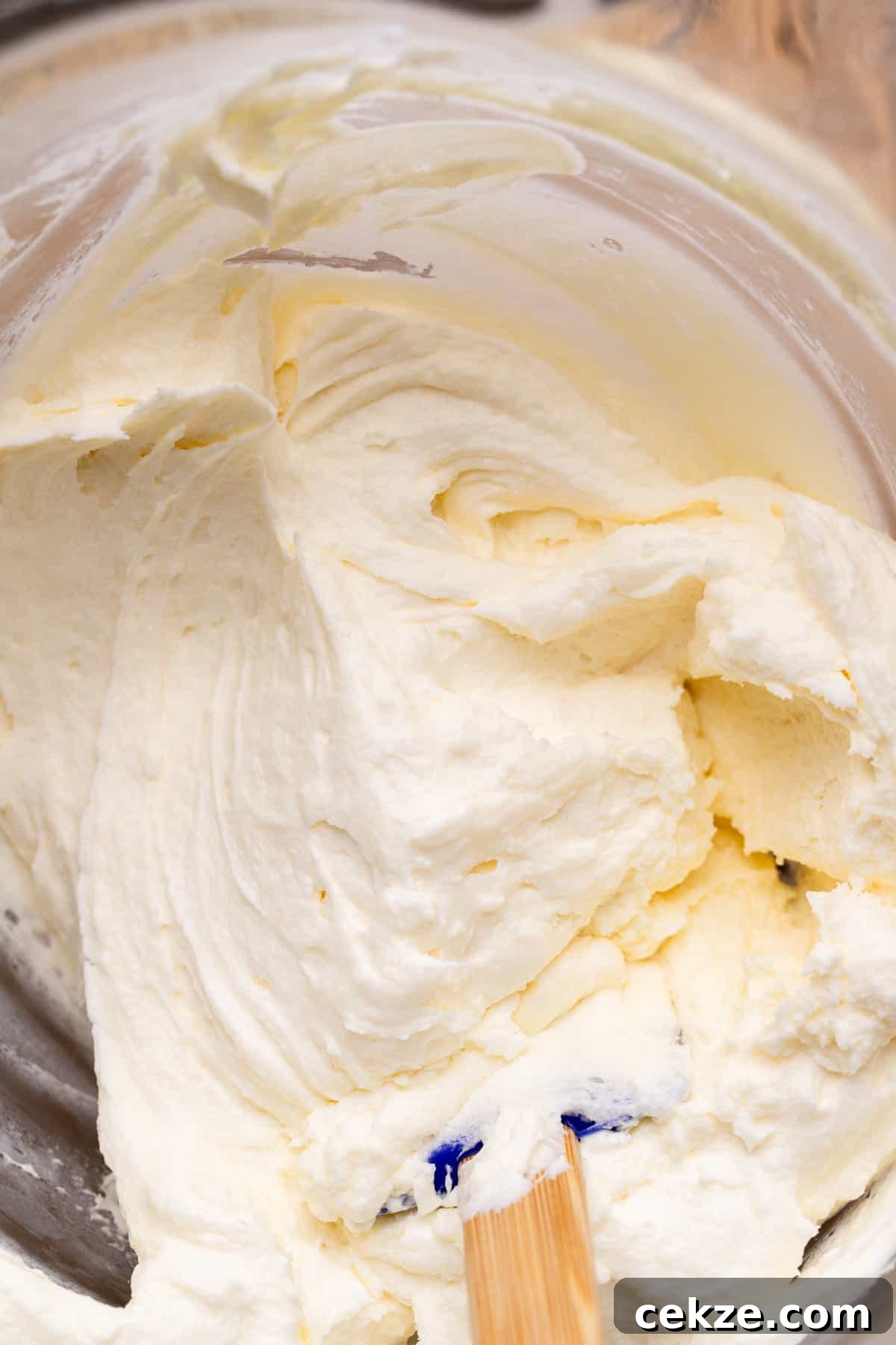 Carrot Cake Cheesecake Recipe: Moist Layered Dessert with Cream Cheese Frosting 10 Cream cheese frosting in a glass bowl.