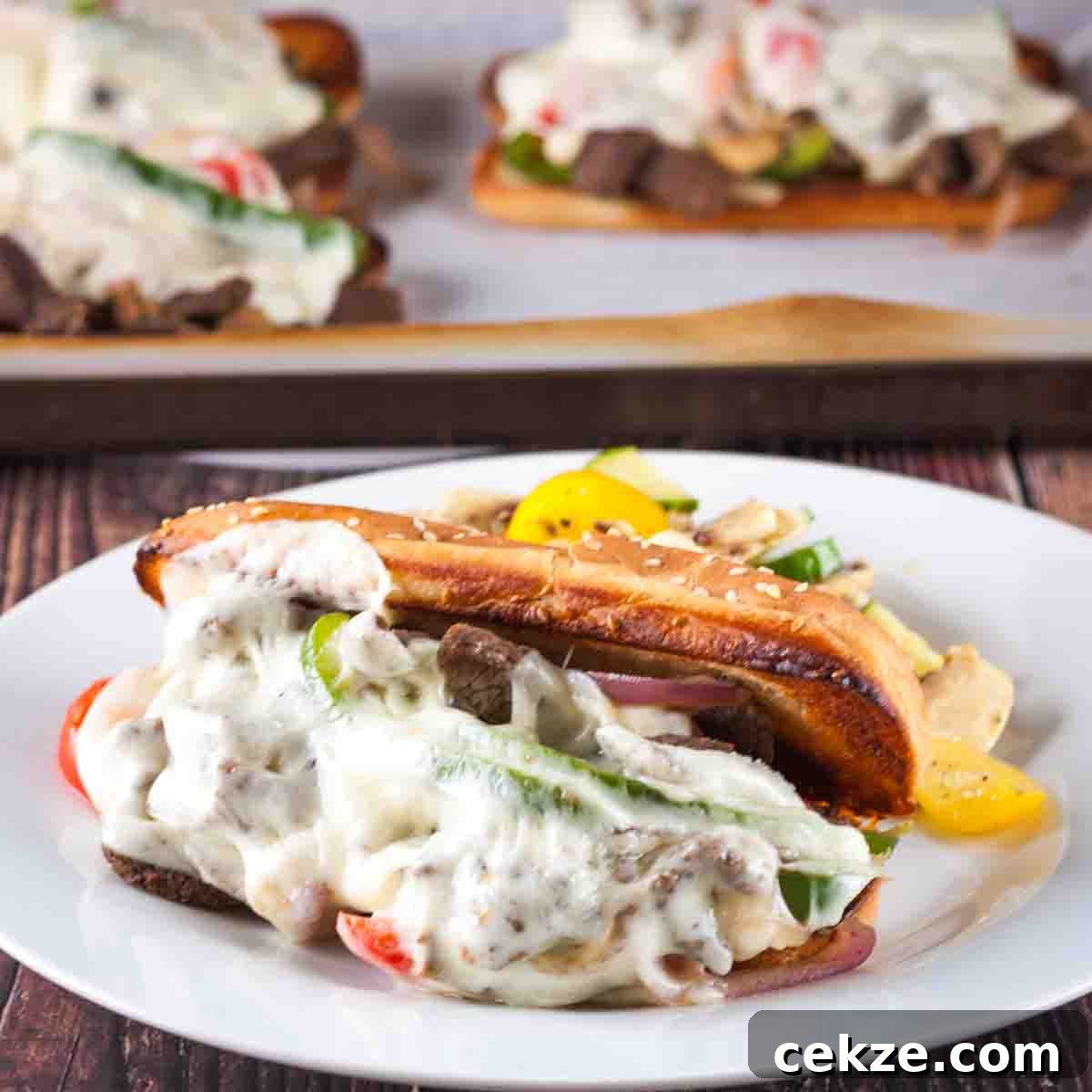 A venison cheesesteak sandwich on a dinner plate with the baking sheet in the background.