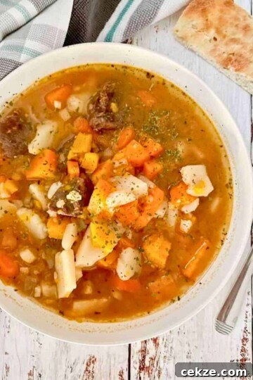 Instant pot venison stew in a white bowl with Focaccia bread on the side.