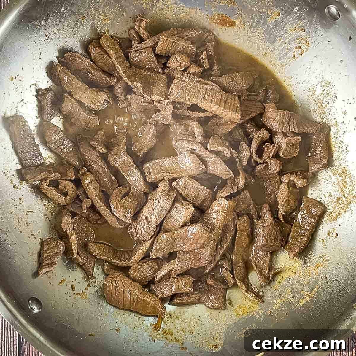 The cooked venison strips in a large skillet.