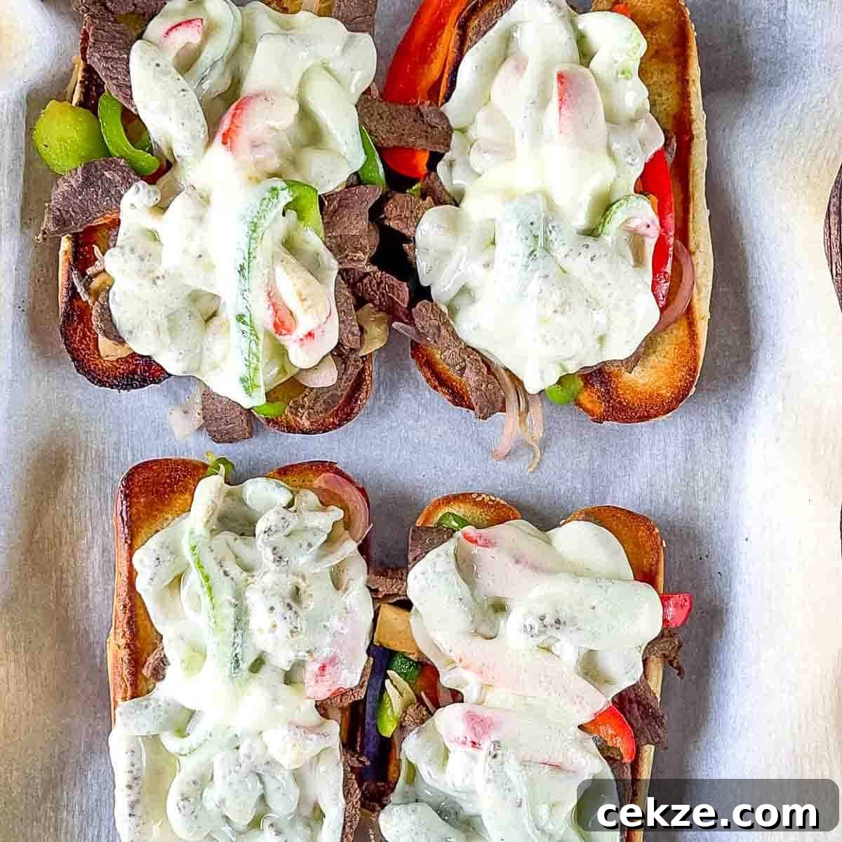 The prepared Philly cheesesteak sandwiches on a baking sheet.