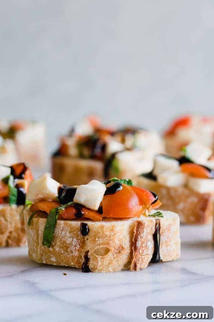 Caprese Bruschetta on top of sliced baguette and drizzled with a balsamic glaze.