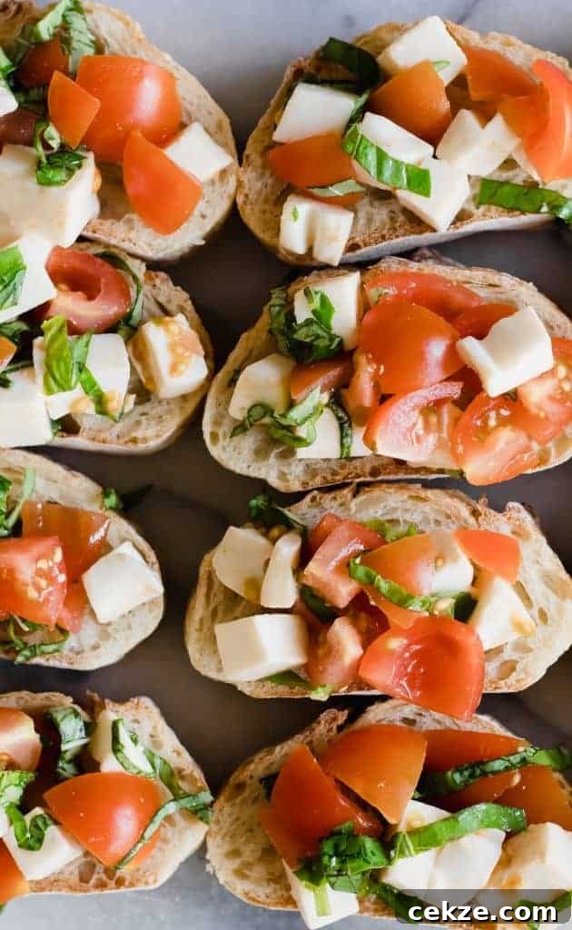 Bread slices laid out and topped with caprese bruschetta, fresh tomatoes, mozzarella and basil.