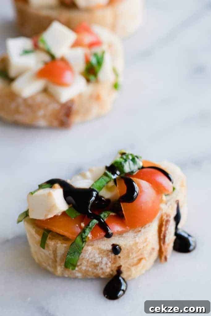 Caprese Bruschetta on top of sliced baguette and drizzled with a balsamic glaze.
