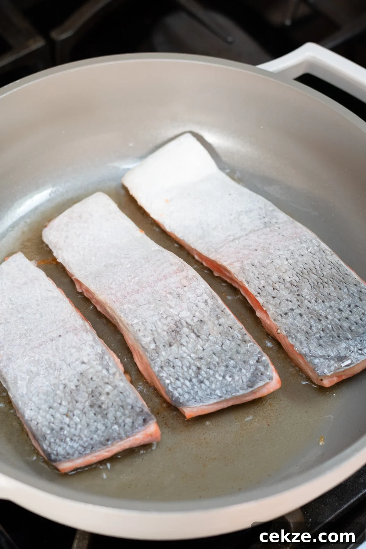 Salmon fillets cooking flesh side down in nonstick skillet