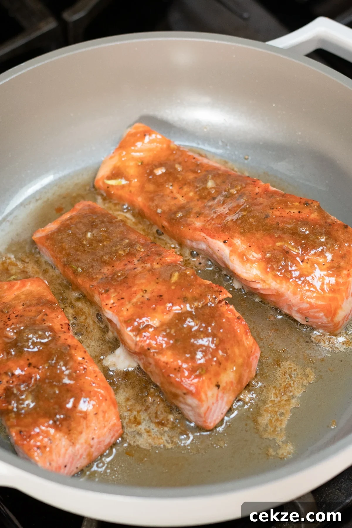 Salmon fillets skin side down in skillet with miso butter sauce on top