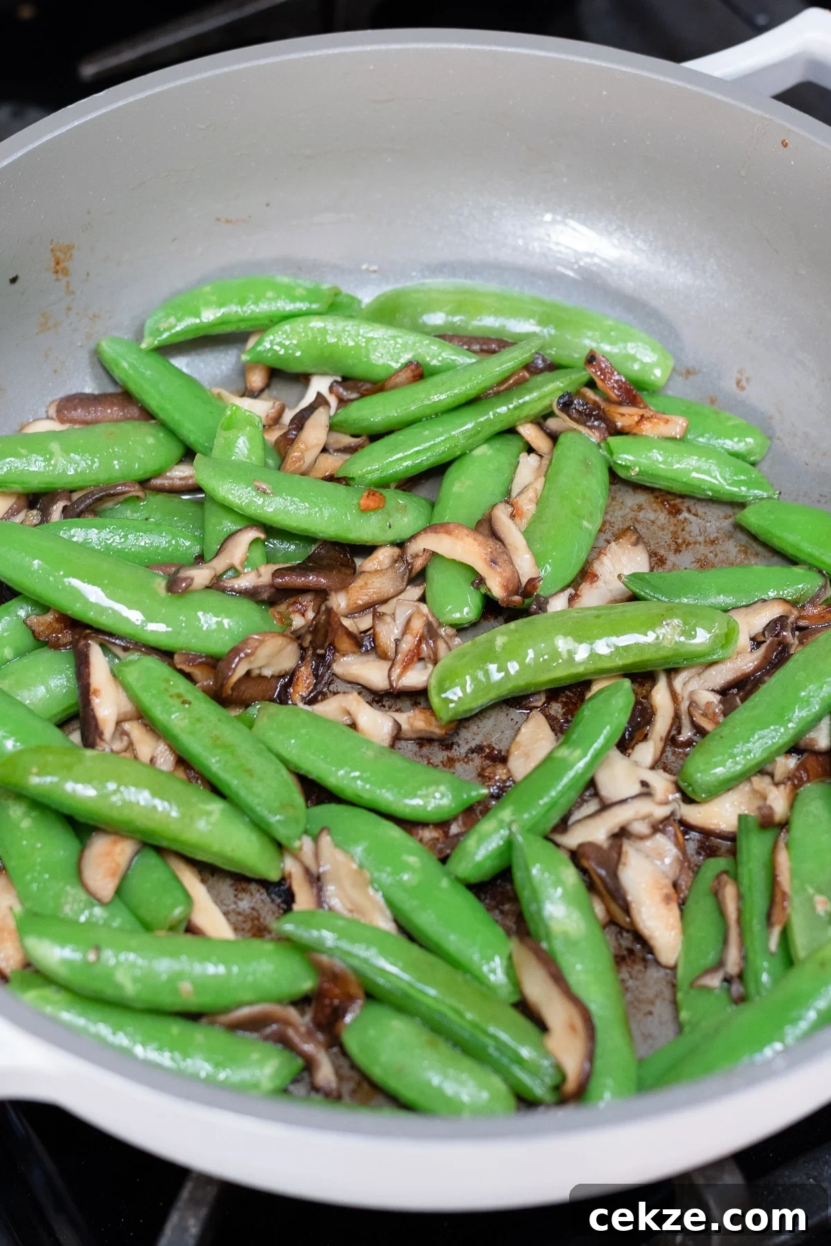 Snap peas and mushrooms sautéing in pan