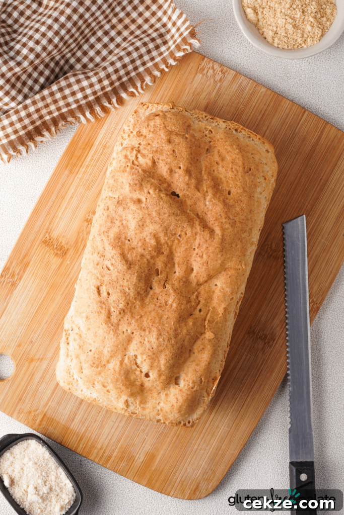 An uncut loaf of gluten free bread with a serrated bread knife on a cutting board.