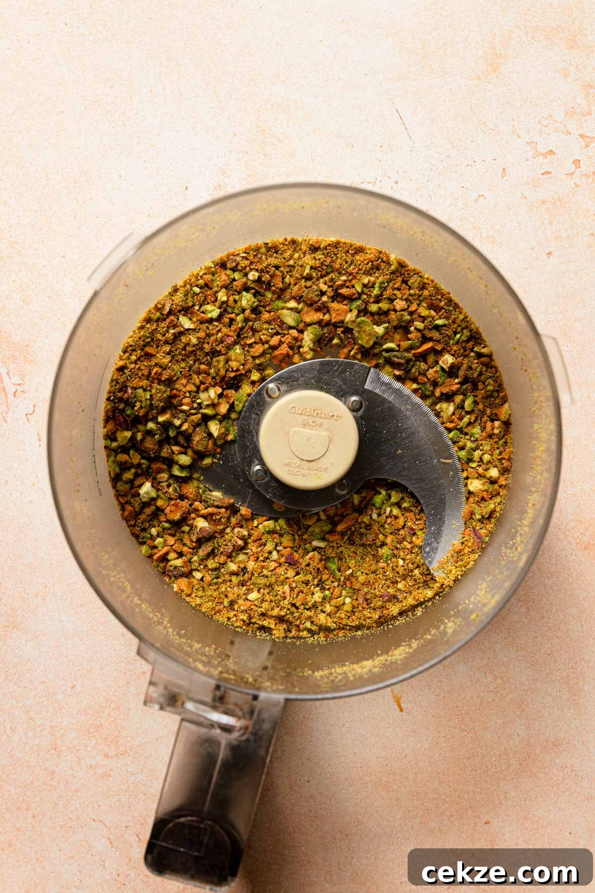 a food processor bowl with ground pistachios.