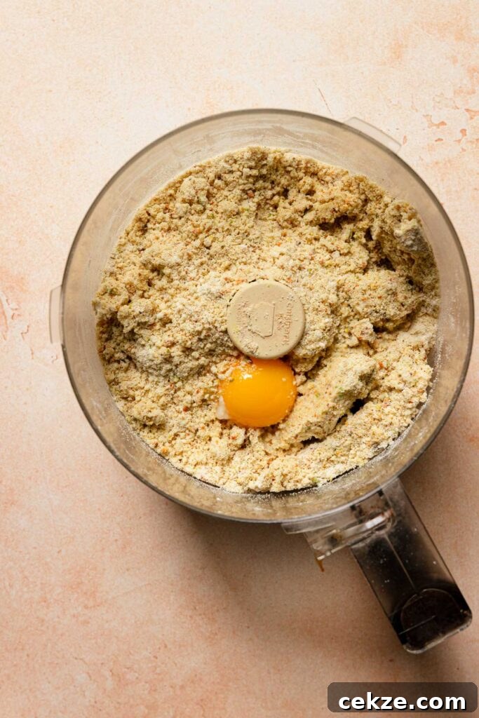 a food processor bowl with flour mixture and an egg yolk.
