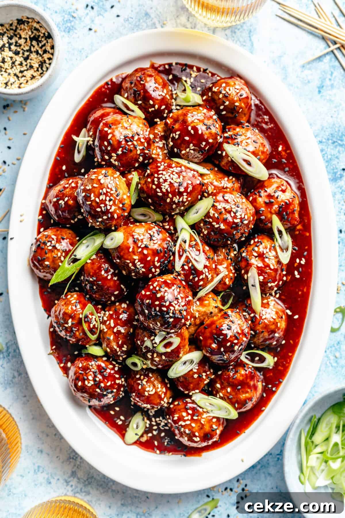 Korean BBQ Chicken Meatballs with Gochujang Glaze 4 Korean-Inspired BBQ Chicken Meatballs on white oval platter.