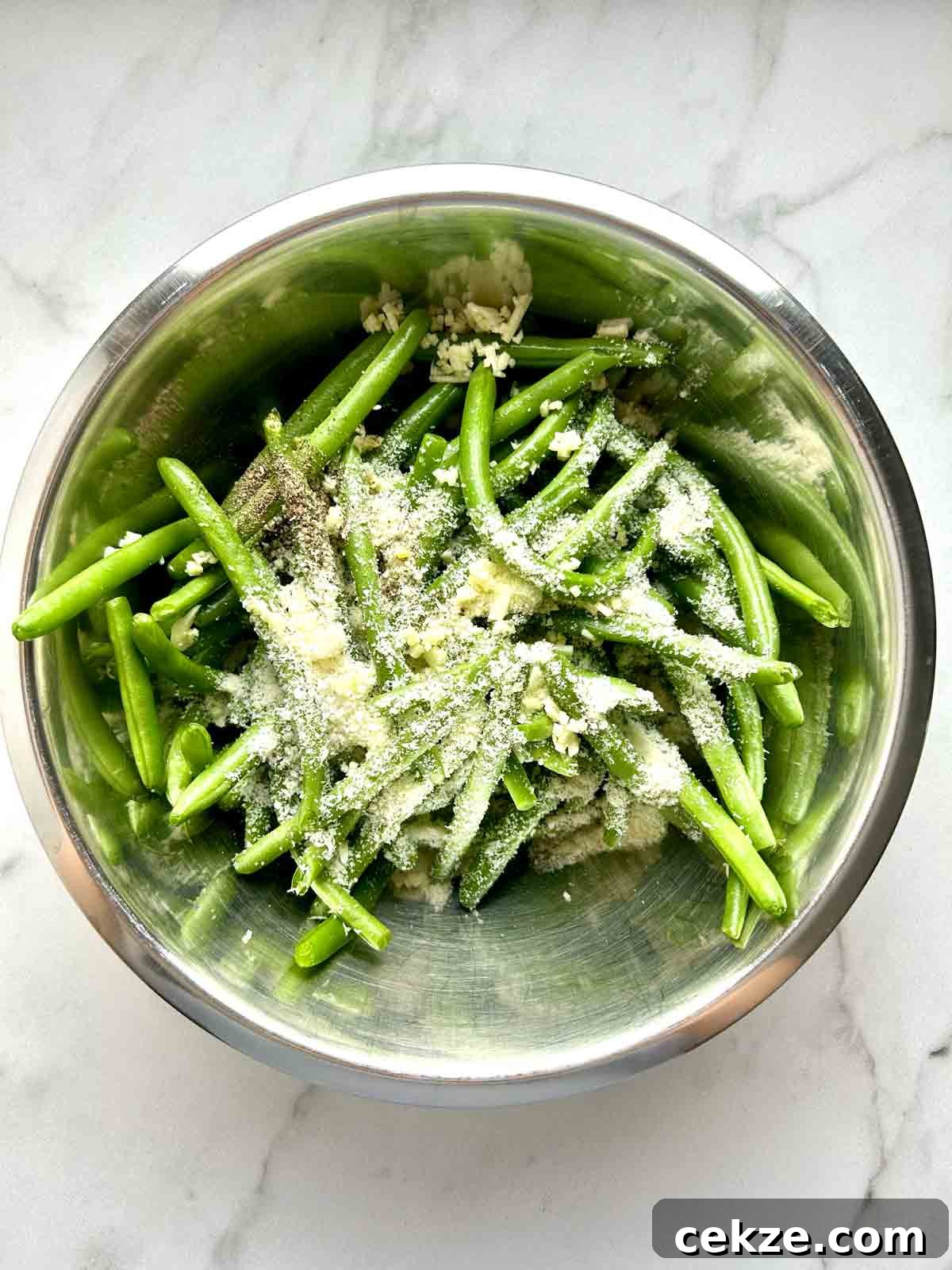 seasonings thrown on top of green beans in bowl.