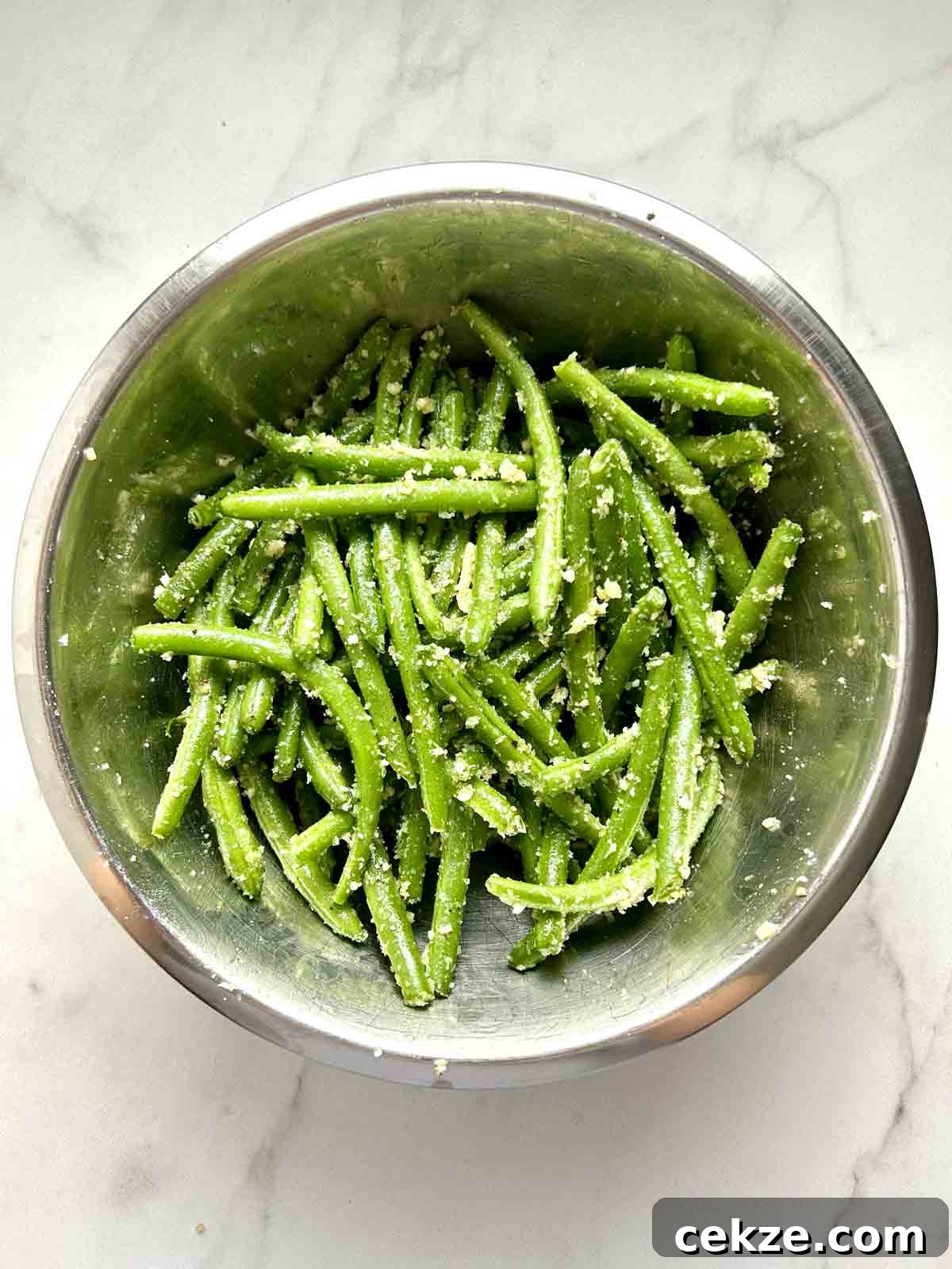 green beans tossed with seasonings in bowl.