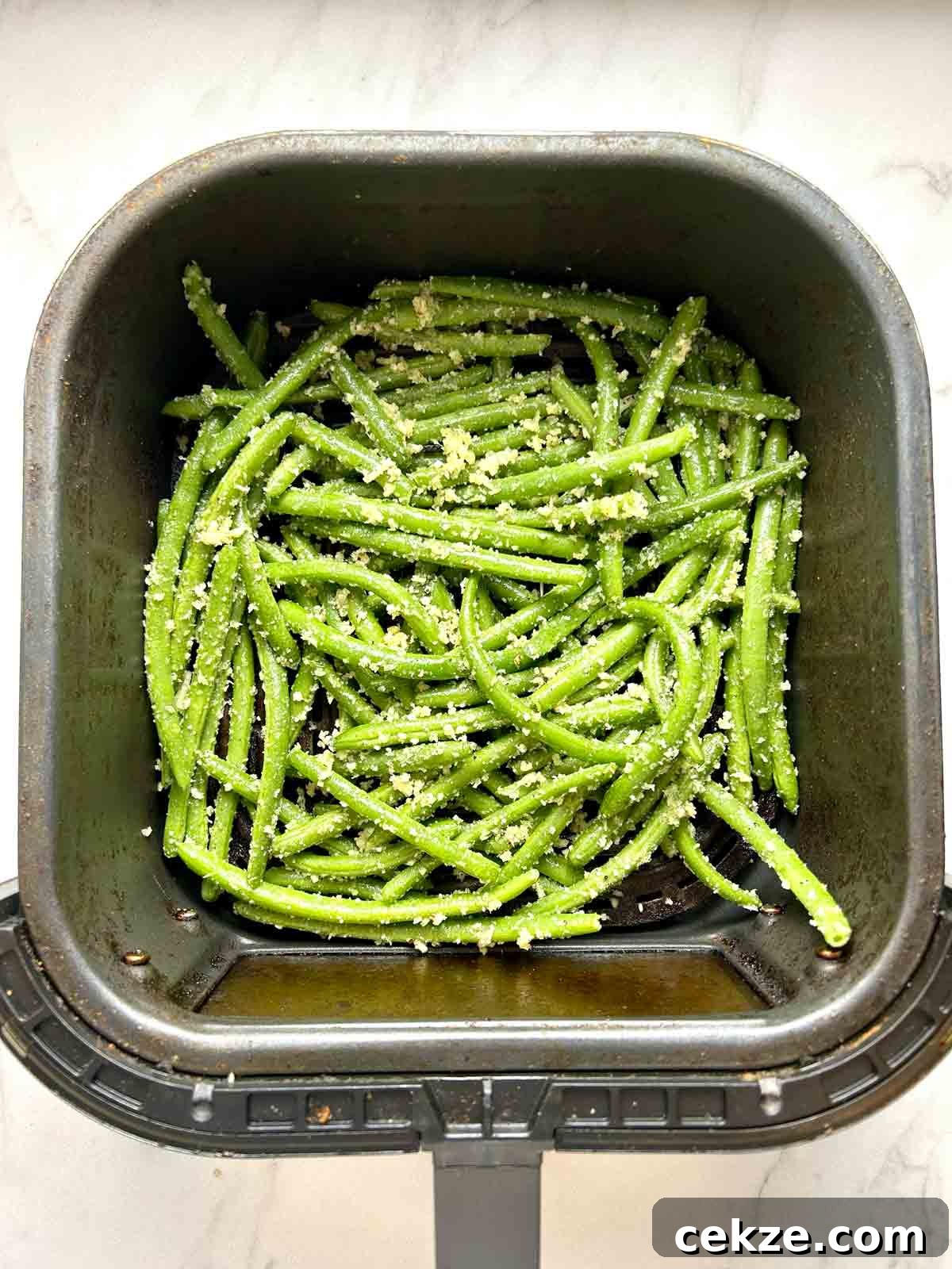 uncooked green beans in air-fryer basket.