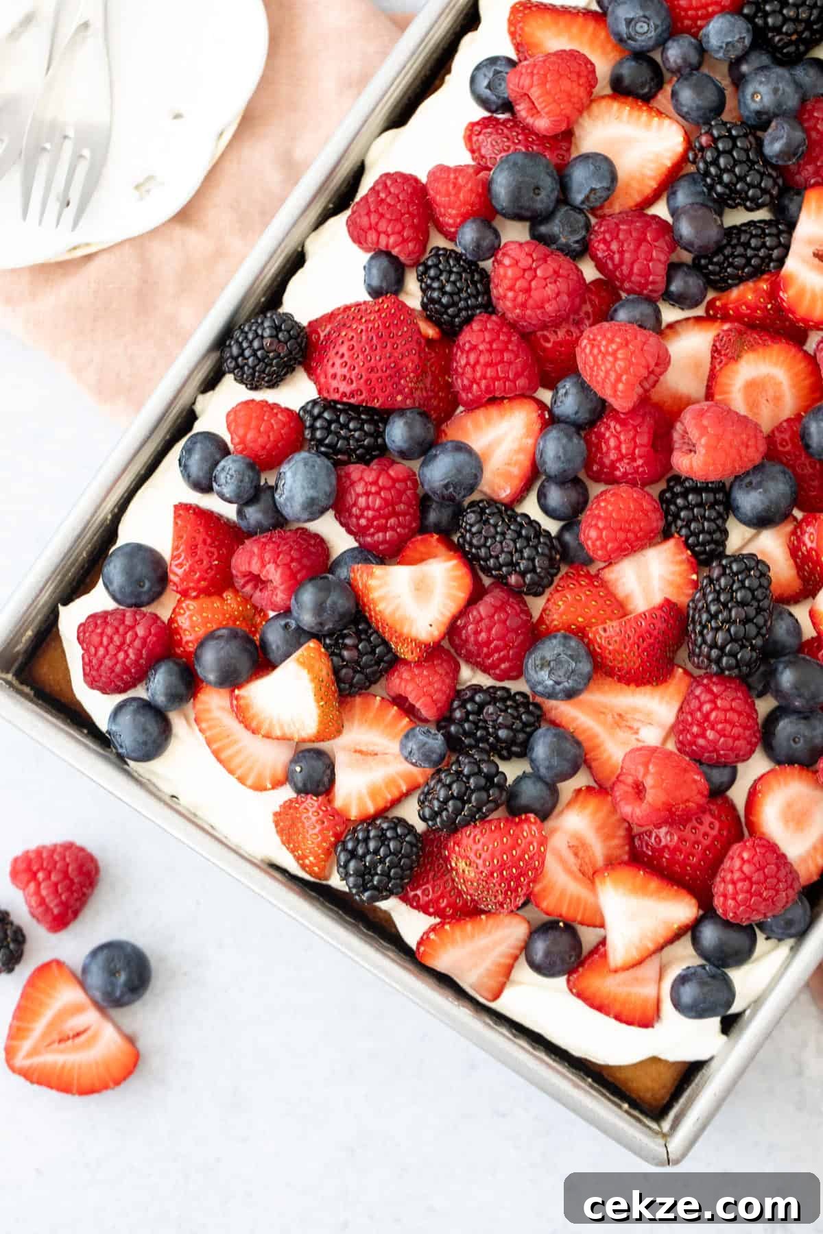 9x13 inch pan of sheet cake topped with whipped cream topping and berries