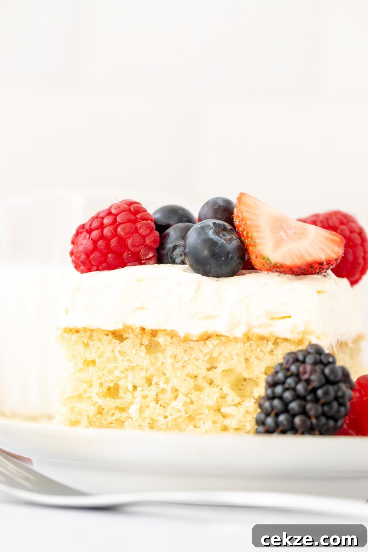 Slice of vanilla cake with whipped cream and fresh berries on top