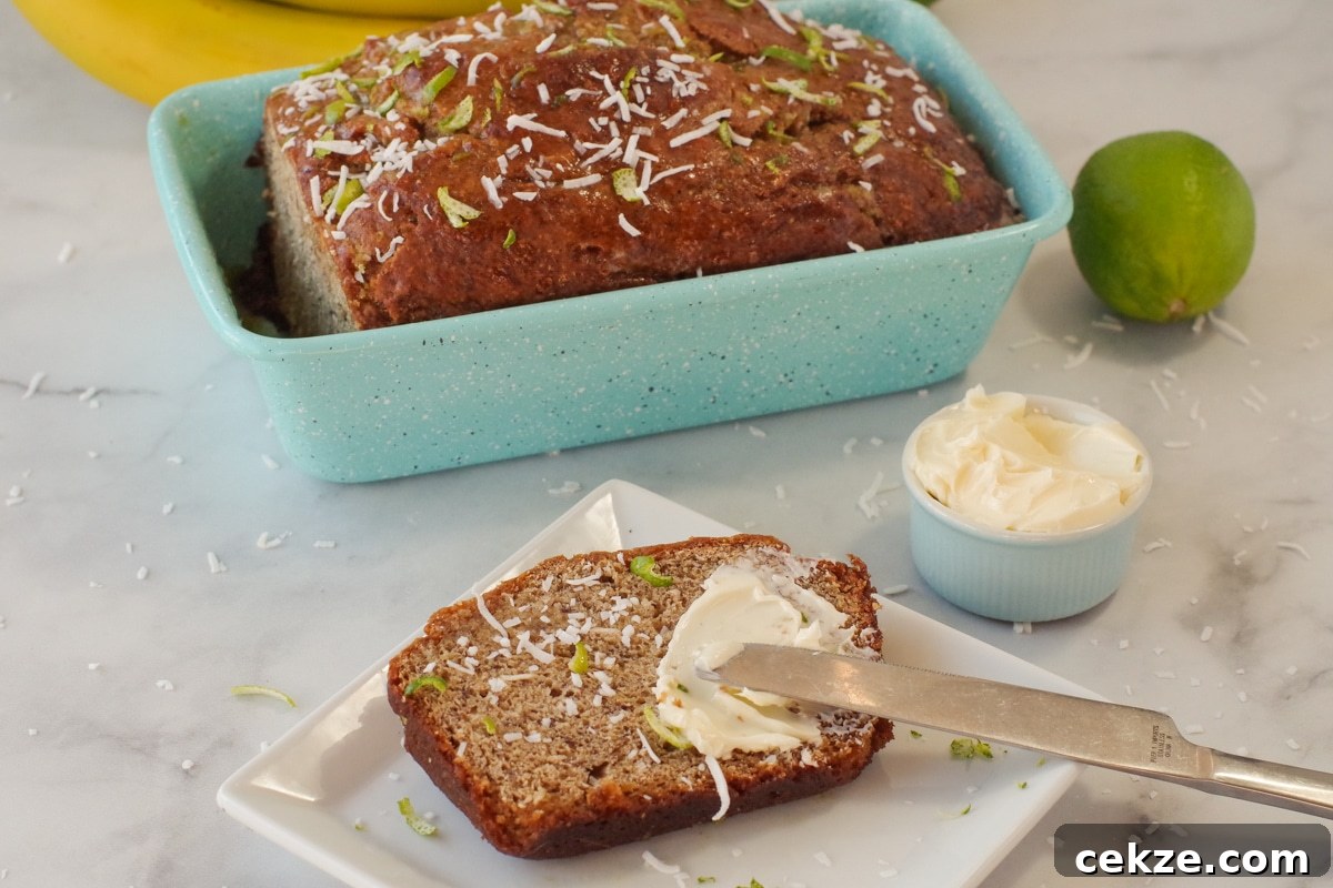 banana bread in blue loaf pan with slice of banana bread on a white plate with butter