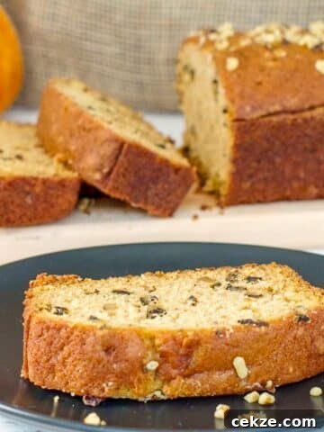 A slice of Dairy-free Pumpkin Bread on a black plate with more in the background.