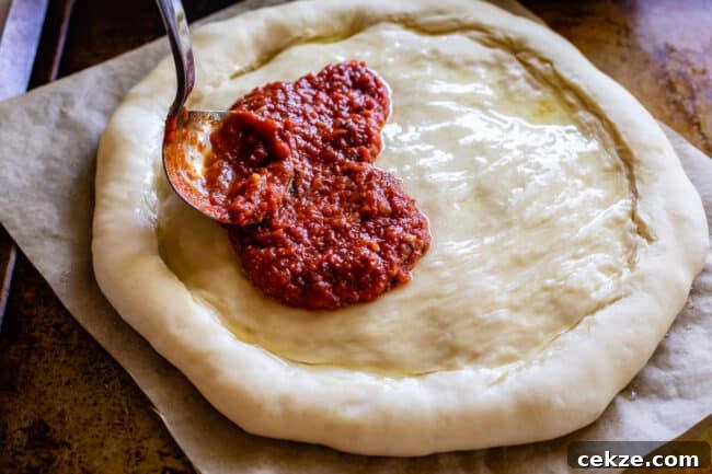 Classic Homemade Pizza Sauce Recipe for Perfect Pies 8 easy pizza sauce being spread on raw dough.