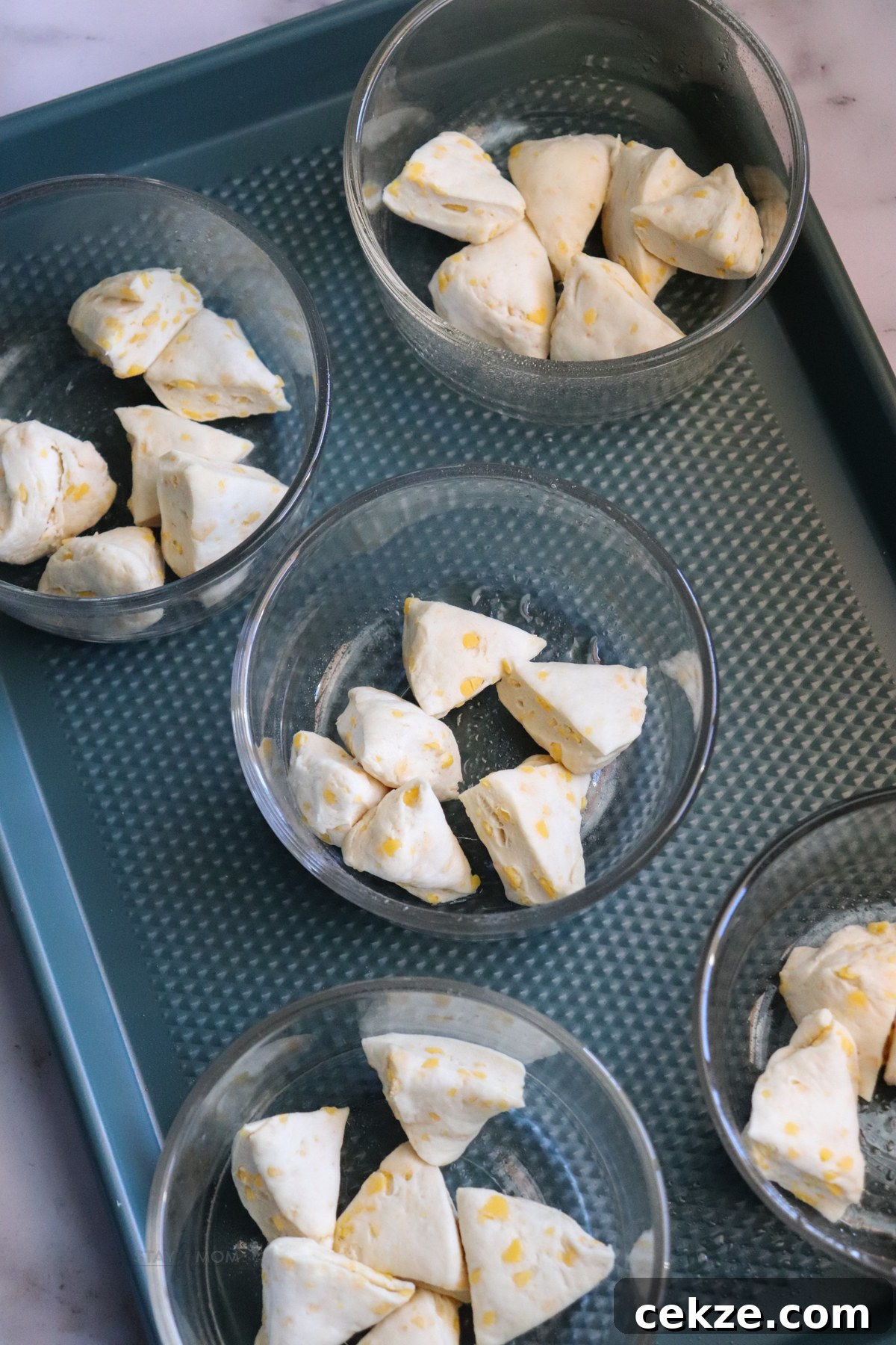 Biscuits and Gravy Casseroles showing 5 oven-save containers on a baking sheet with cut up biscuits in the bottom.