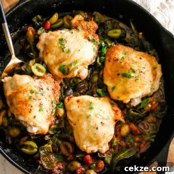 basque chicken in a skillet with a serving spoon.