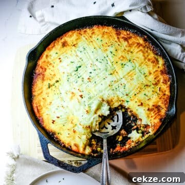 shepherd's pie in a cast iron skillet with a spoon.