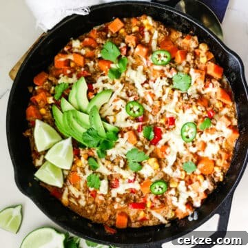 Ground beef and sweet potato in a skillet with lime and parsley beside it.