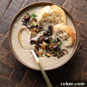 Mushroom and Bean Soup Bowl topped with sliced sauteed mushrooms, parsley, and torn baguette