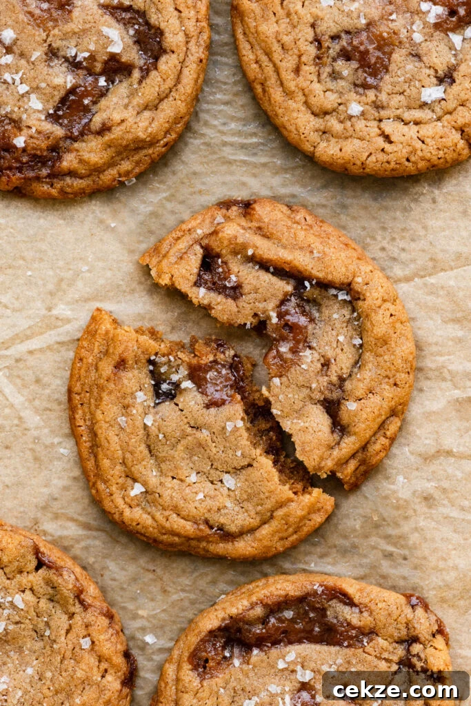 Brown Sugar Toffee Cookies Recipe — Chewy Caramelized Treats 2 Closeup of a toffee cookie broken in half on a piece of parchment paper.