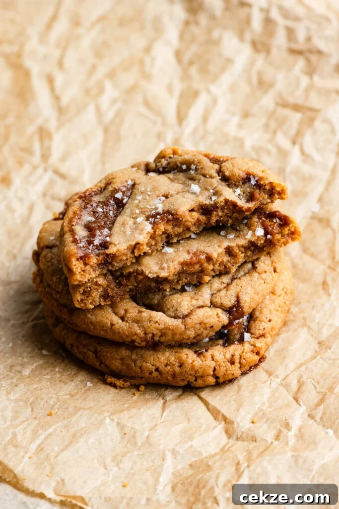Brown Sugar Toffee Cookies Recipe — Chewy Caramelized Treats 8 Stack of cookies filled with toffee and the top cookie is broken in half.
