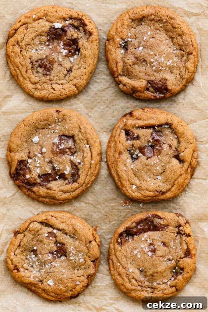 Brown Sugar Toffee Cookies Recipe — Chewy Caramelized Treats 9 Six large cookies baked with chunks of melted toffee in them on a parchment paper lined tray.