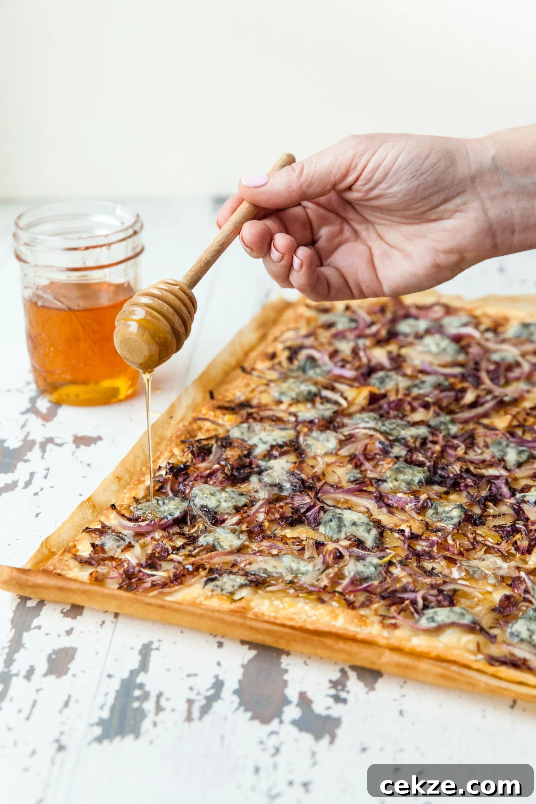 Drizzling honey over flatbread strips with Blue Cheese, Radicchio, and Onion.