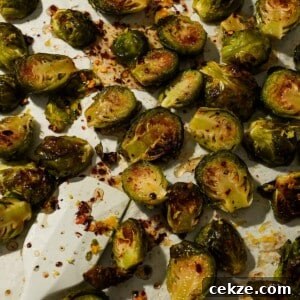 Roasted Hot Honey Brussels Sprouts (5-Ingredient Recipe) 12 Roasted Brussels sprouts with chili flakes and honey glaze scattered on parchment.