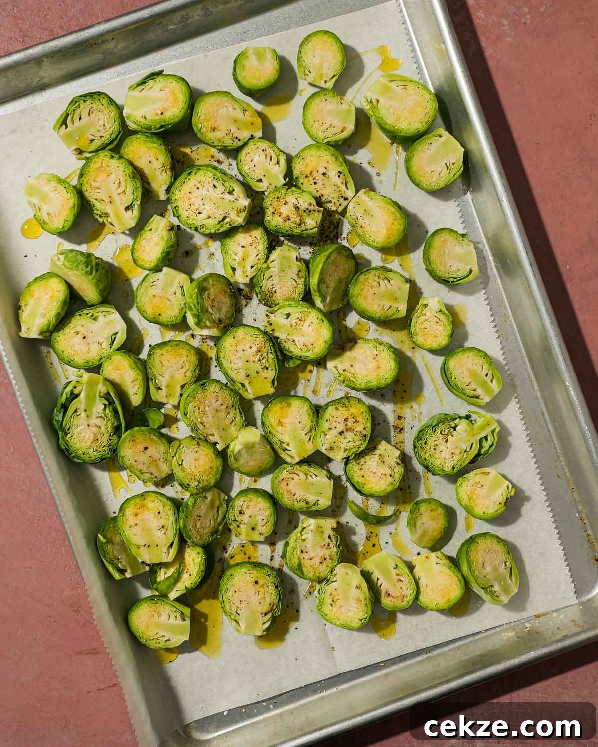 Roasted Hot Honey Brussels Sprouts (5-Ingredient Recipe) 4 Halved raw Brussels sprouts seasoned with oil, salt, and pepper on a tray.