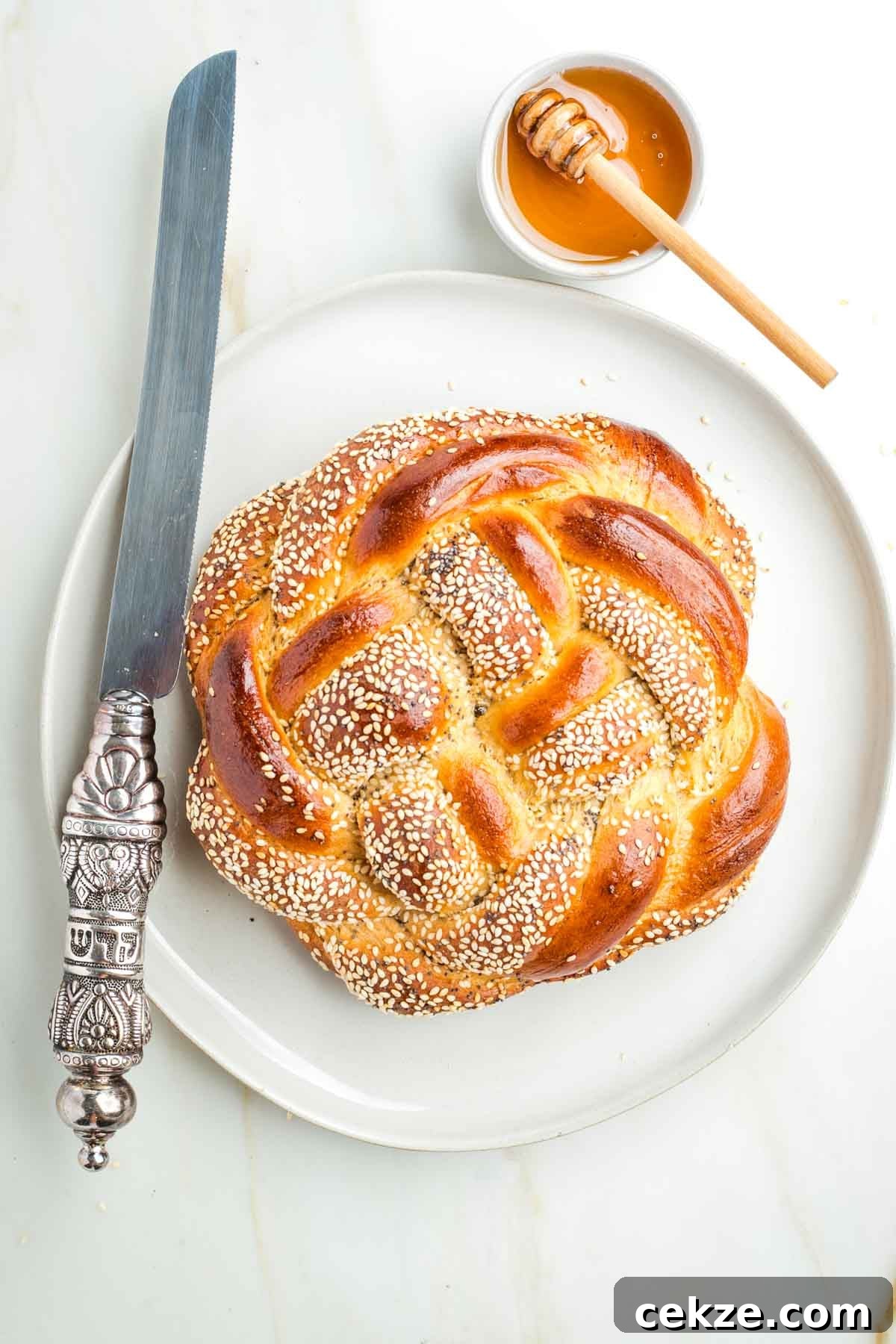 Sweet Round Challah Recipe: Soft, Shiny Braided Dinner Bread 2 Round, braided challah, sprinkle with seeds, a dish of honey plus a serrated challah knife.