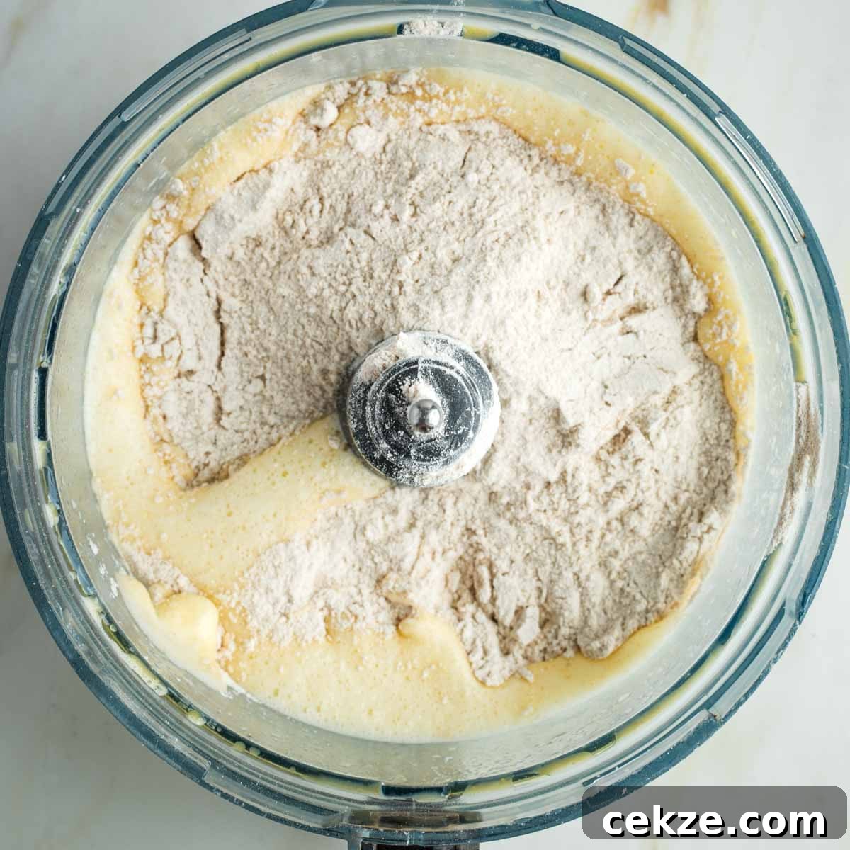 Sweet Round Challah Recipe: Soft, Shiny Braided Dinner Bread 11 Flour sprinkled on top of yeast and egg mixture in the bowl of a food processor.