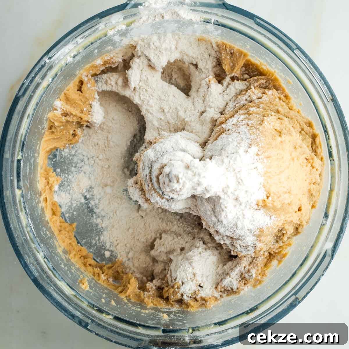 Sweet Round Challah Recipe: Soft, Shiny Braided Dinner Bread 15 Flour sprinkled onto sticky bread dough in the bowl of a food processor.